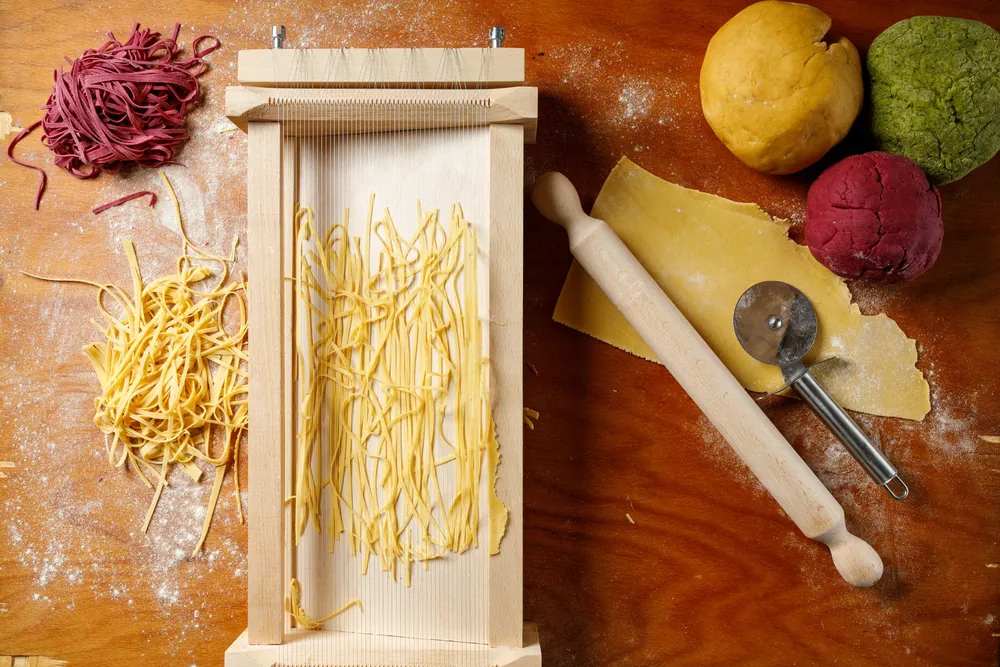 Aluat de paste în trei culori, foaie întinsă cu sucitorul și tagliatelle tăiate pe chitarra
